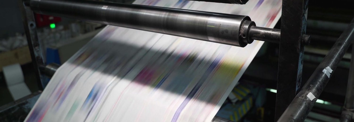 Freshly printed pages racing through the rollers of a commercial printing press